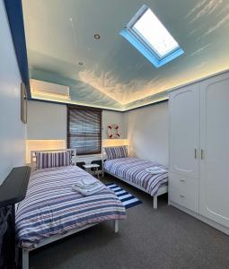 a bedroom with two beds and a skylight at 8 Ravenscourt Gardens in London