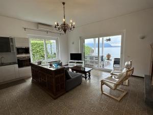 un soggiorno con lampadario pendente, divano e sedie di Villa Anastasye Your Lakefront Vacation Rental a Predore