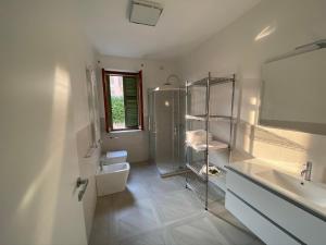 bagno bianco con doccia e lavandino di Villa Anastasye Your Lakefront Vacation Rental a Predore