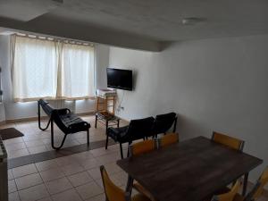 sala de estar con mesa, sillas y TV en La Escondida en Ushuaia