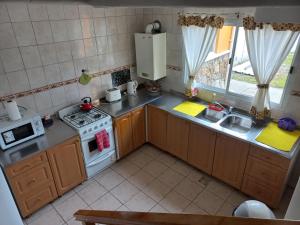 Una pequeña cocina con estufa y fregadero. en La Escondida, en Ushuaia 10 fotos más