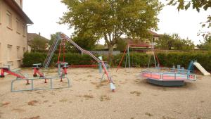 un parque infantil con 2 columpios y un tobogán en Le Bel Air en Mions