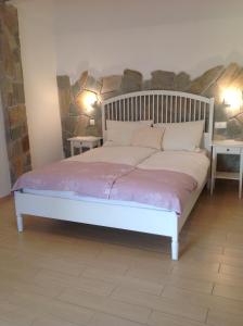 een wit bed in een kamer met 2 tafels bij T H E BERLIN Studios and Suites in Nea Vrasna