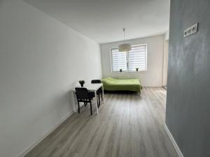 Jest to biały pokój ze stołem i zielonym łóżkiem. w obiekcie Apartament Katowicka w Poznaniu