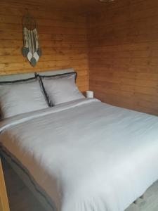 a bedroom with a white bed with a wooden wall at Winiec Mobile Home in Miłomłyn