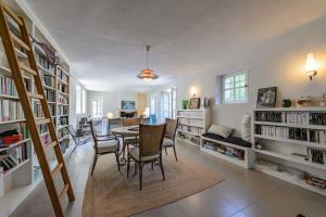 een woonkamer met een tafel en stoelen en boekenplanken bij Mas provençal avec piscine et tennis in Oppède