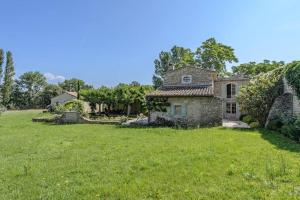 een oud stenen huis in een grasveld bij Mas provençal avec piscine et tennis in Oppède