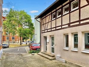 エアフルトにあるDIE REMISE mit kostenlosem Parkplatz direkt vor der Türの道路の横に赤い車が駐車されている建物