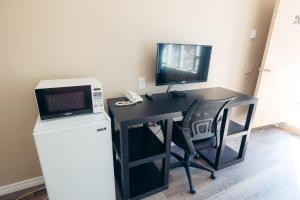 escritorio negro con microondas y TV en Clarkson Village Motel, en Mississauga