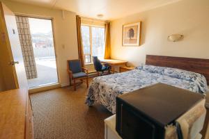 a bedroom with a bed and a desk and a window at Clarkson Village Motel in Mississauga