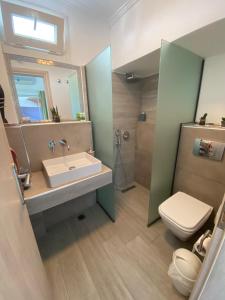 een badkamer met een wastafel, een toilet en een spiegel bij T H E BERLIN Studios and Suites in Nea Vrasna