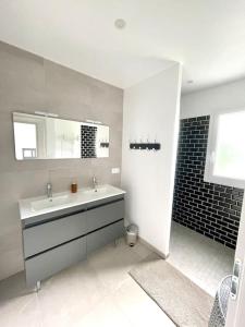 bagno bianco con lavandino e specchio di Le Logis de Pomerol a Pomerol