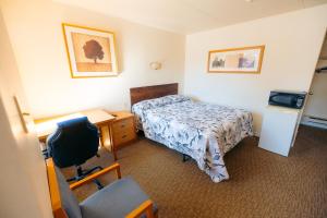 a hotel room with a bed and a desk and a chair at Clarkson Village Motel in Mississauga