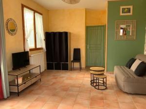uma sala de estar com um sofá e uma televisão em Gites l’Olivier avec piscine em Vallon-Pont-dʼArc