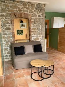sala de estar con sofá y pared de piedra en Gites l’Olivier avec piscine, en Vallon-Pont-dʼArc