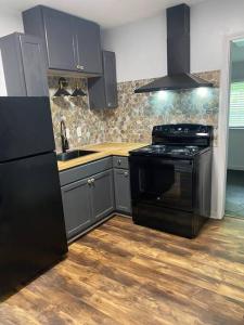 uma cozinha com um fogão preto e um lavatório em Charming Cozy Cottage Near Southern University! em Baton Rouge