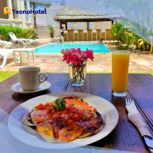 a table with a plate of food and a glass of orange juice at Tecnohotel Casa Villamar in Progreso