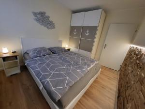 - une chambre avec un lit et une couette grise dans l'établissement FeWo Dünengras mit Terrasse und Strandkorb, à Lübeck