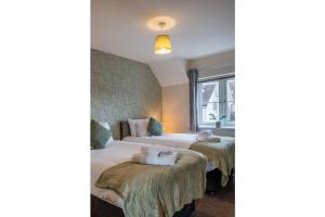 twee bedden in een hotelkamer met handdoeken op de bedden bij Towpath Gardens Apartment (Free Parking and Central) in Swindon