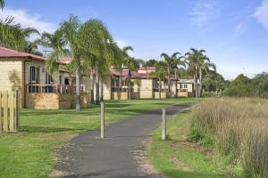 a road in front of a house with palm trees at Discovery Parks - Bunbury Foreshore in Bunbury