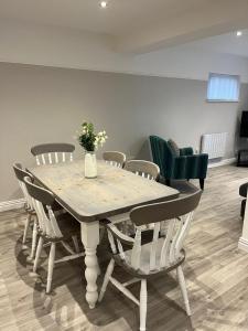 a dining room table with chairs and a vase with flowers at Ty glan y mor in Tremadoc