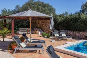 a patio with chairs and an umbrella next to a pool at Beautiful Countryside Villa w Private Garden and Pool in Alte