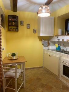cocina con paredes amarillas, mesa y fregadero en Casetta del Rione, en Rocca di Mezzo