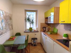 a kitchen with yellow cabinets and a table with green chairs at GreenApartament in Krakow