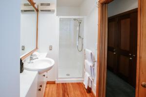 a white bathroom with a shower and a sink at Bullock Creek Chalet - Sleeps 8 - Lake & Mountain Views - Private & Secluded in Wanaka