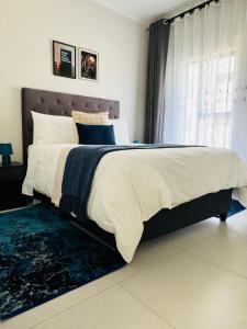 1 dormitorio con 1 cama grande con alfombra azul en Liams blue suite at 93 On New, en Midrand