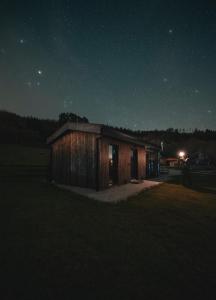 un pequeño edificio de madera en un campo por la noche en Cabañas O Recuncho do Sor, en O Barqueiro