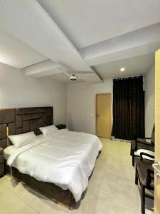 - une chambre avec un grand lit blanc et un bureau dans l'établissement Essence Homes, à Islamabad