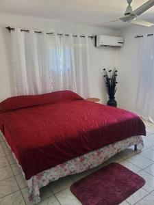 um quarto com uma cama vermelha com cortinas e tapetes em Evelin's On The Beach em Montego Bay