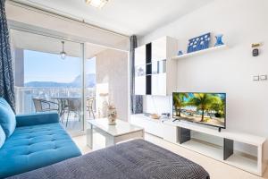 ein Wohnzimmer mit einer blauen Couch und einem Fernseher in der Unterkunft Tower San Remo 9-E Apartment Levante Beach in Benidorm