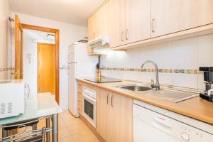 een keuken met witte apparaten en houten kasten bij Tower San Remo 9-E Apartment Levante Beach in Benidorm