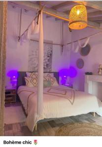 een slaapkamer met een wit bed met paarse verlichting bij Love Appart Balnéo Jacuzzi Romantique Insolite in Le Barroux