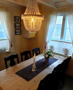 a dining room table with a candle and a chandelier at Kvammehuset på Gamle Lærdalsøyri in Lærdalsøyri