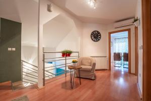 a living room with a chair and a table and a clock at Apartment Premier in Bjelovar
