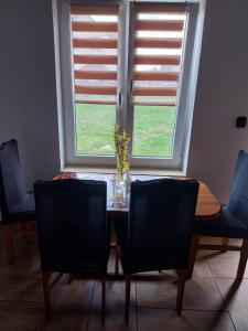 a dining room table with chairs and a vase with flowers at Noclegi u Lucyny in Chęciny +13 photos