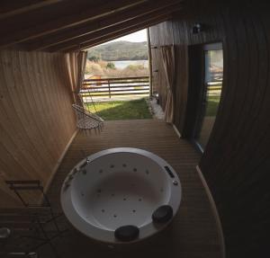 Habitación con ventana y vistas a la bañera. en Cabañas O Recuncho do Sor en Porto do Barqueiro