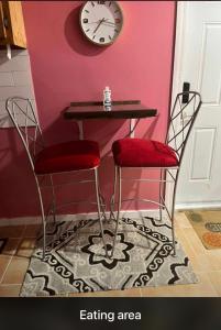 une table avec deux chaises et une horloge sur un mur dans l'établissement SanAndros Airbnb, à Marsh Harbour