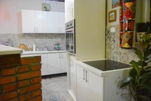 a kitchen with white cabinets and a brick wall at White Arrow Apartment in Bajina Bašta