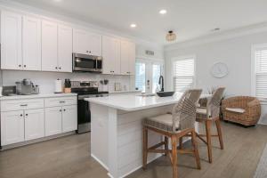 a kitchen with white cabinets and a table and chairs at Southern Charming NEW Home Mins to Beach & Dwntn in Charleston