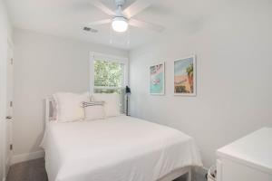 a white bedroom with a bed with a ceiling fan at Southern Charming NEW Home Mins to Beach & Dwntn in Charleston