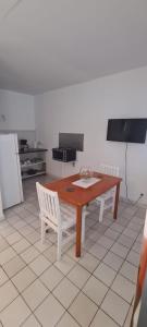 a kitchen with a wooden table and two white chairs at Paradies Caraïbes I in Les Abymes