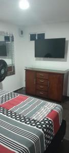 um quarto com uma cama e uma televisão na parede em ApartaSuite El Encanto em Barranquilla