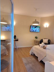 um quarto com uma cama e uma televisão na parede em Villa Prana Guesthouse, Yoga & Ayurveda em Portimão