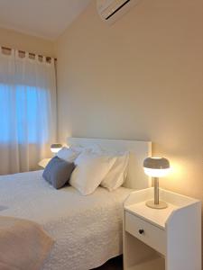 um quarto com uma cama com lençóis brancos e almofadas em Villa Prana Guesthouse, Yoga & Ayurveda em Portimão