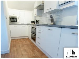 a kitchen with white cabinets and stainless steel appliances at Bright & Spacious Central Apartment in Harrogate