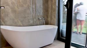 een wit bad in een badkamer met een persoon buiten bij Fruska Gora Villa Medici in Irig